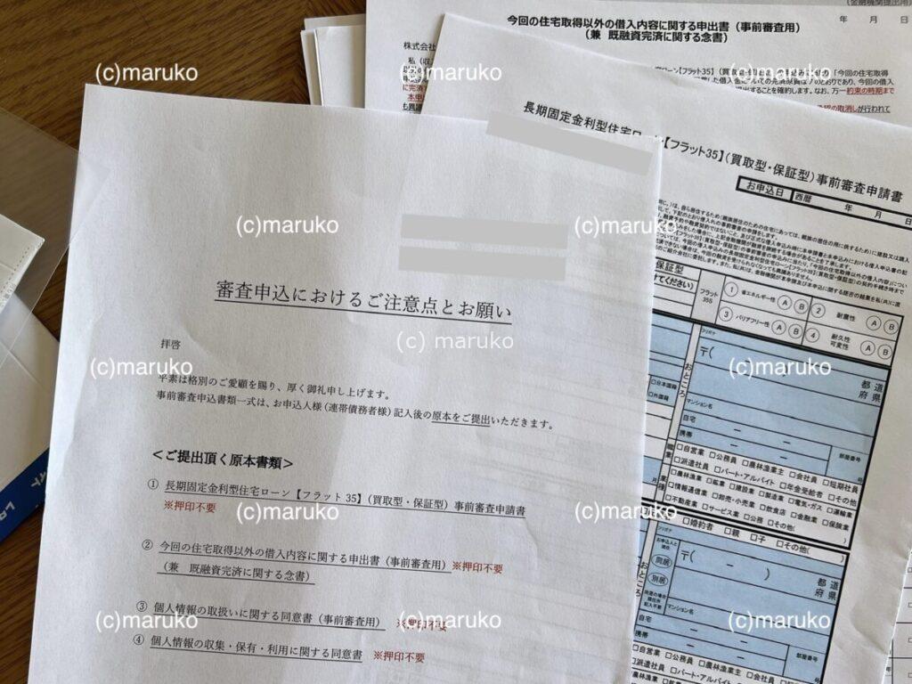 住宅ローン仮審査で郵送された申込書類一式と説明書が机の上に広げられている様子