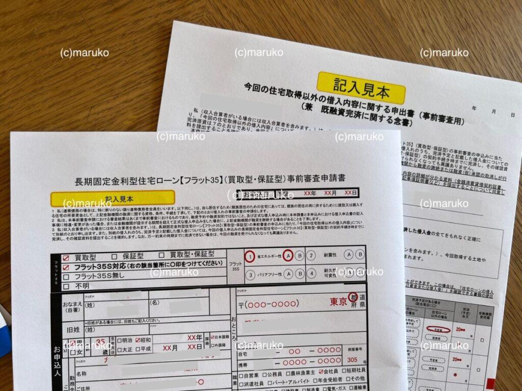 住宅ローン仮審査書類に同封されていた記入例の見本。フラット35などの申込内容の書き方が示された用紙が机の上に並べられている様子