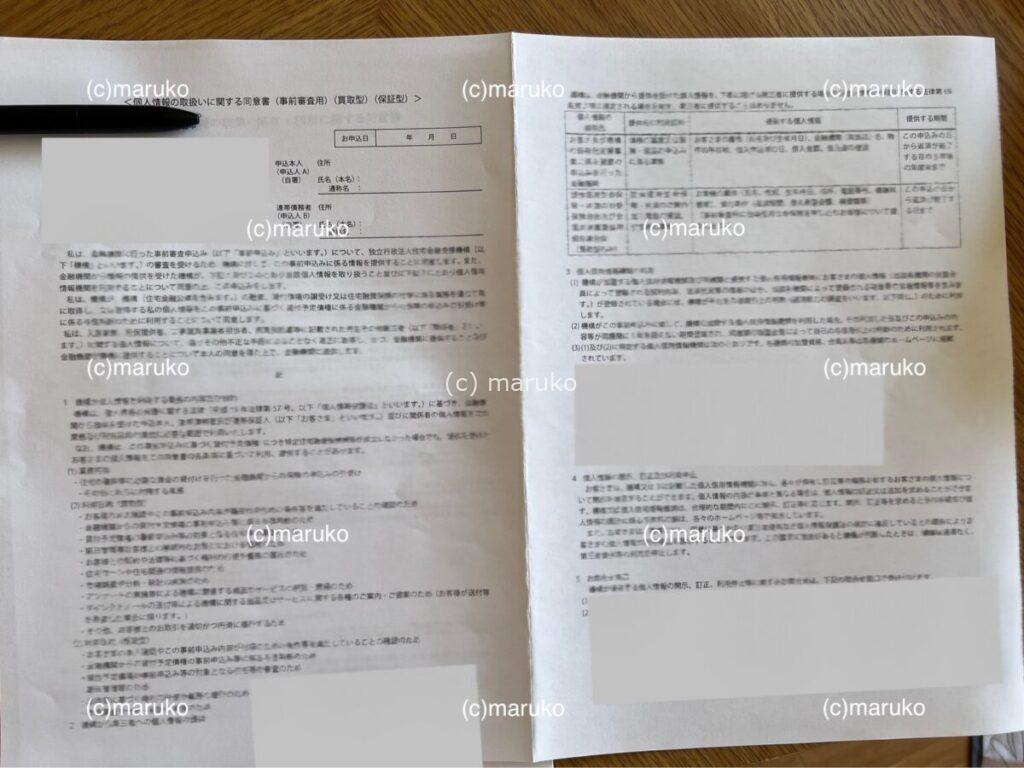 住宅ローン仮審査で必要な同意書1枚目。個人情報の利用目的や取り扱いに関する説明が書かれた書類が机に並べられている様子